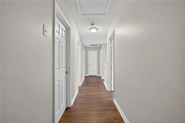 a view of a hallway with wooden floor and a bathroom