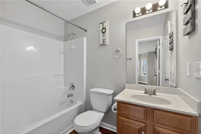 a bathroom with a toilet a sink a mirror a bathtub and vanity