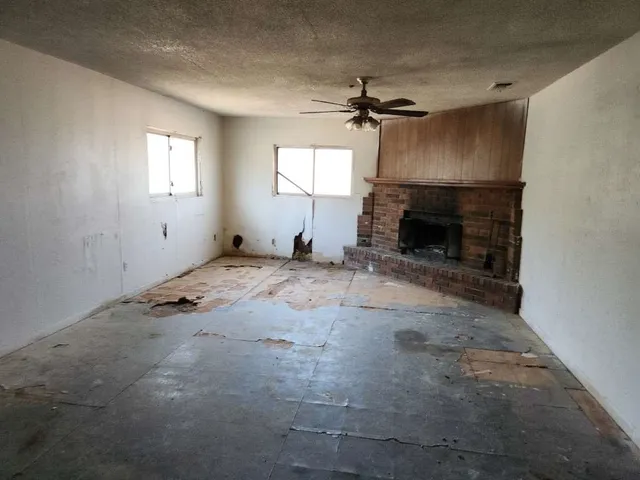 an empty room with windows and fireplace