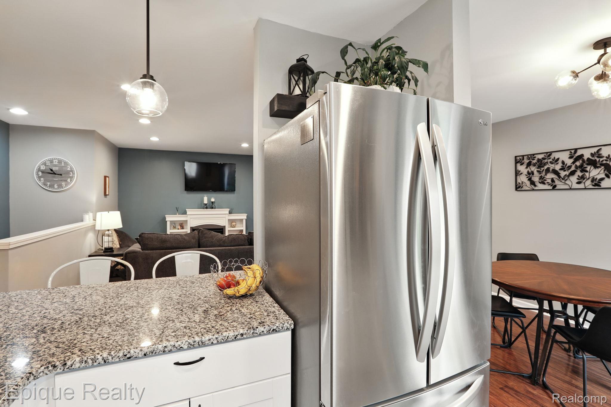8529 22 Mile Road Utica, MI 48317 - Photo 20 of 40 Kitchen featuring freestanding refrigerator, dark wood finished floors, pendant lighting, light stone countertops, and white cabinetry