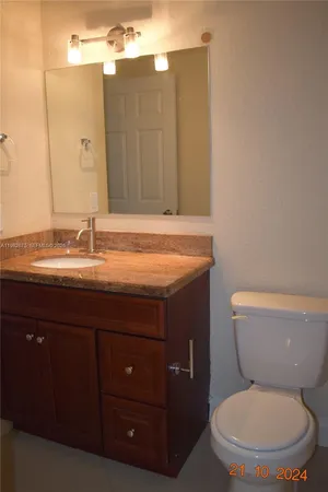 a bathroom with a granite countertop toilet sink and mirror