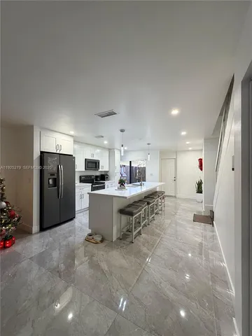 a living room with stainless steel appliances furniture a rug and a kitchen view