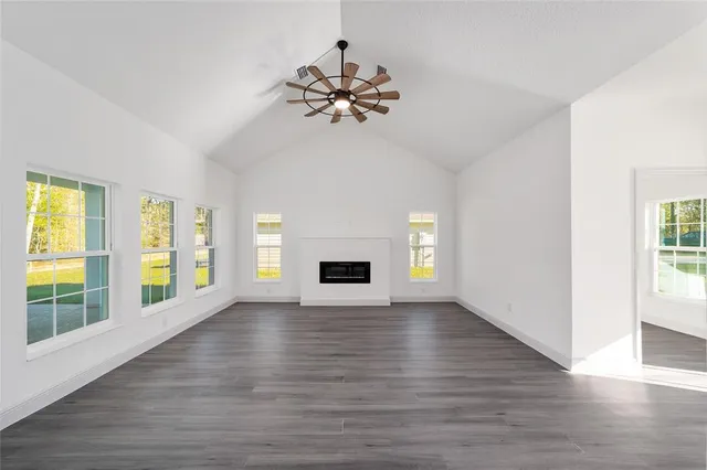a view of an empty room with a window and wooden floor