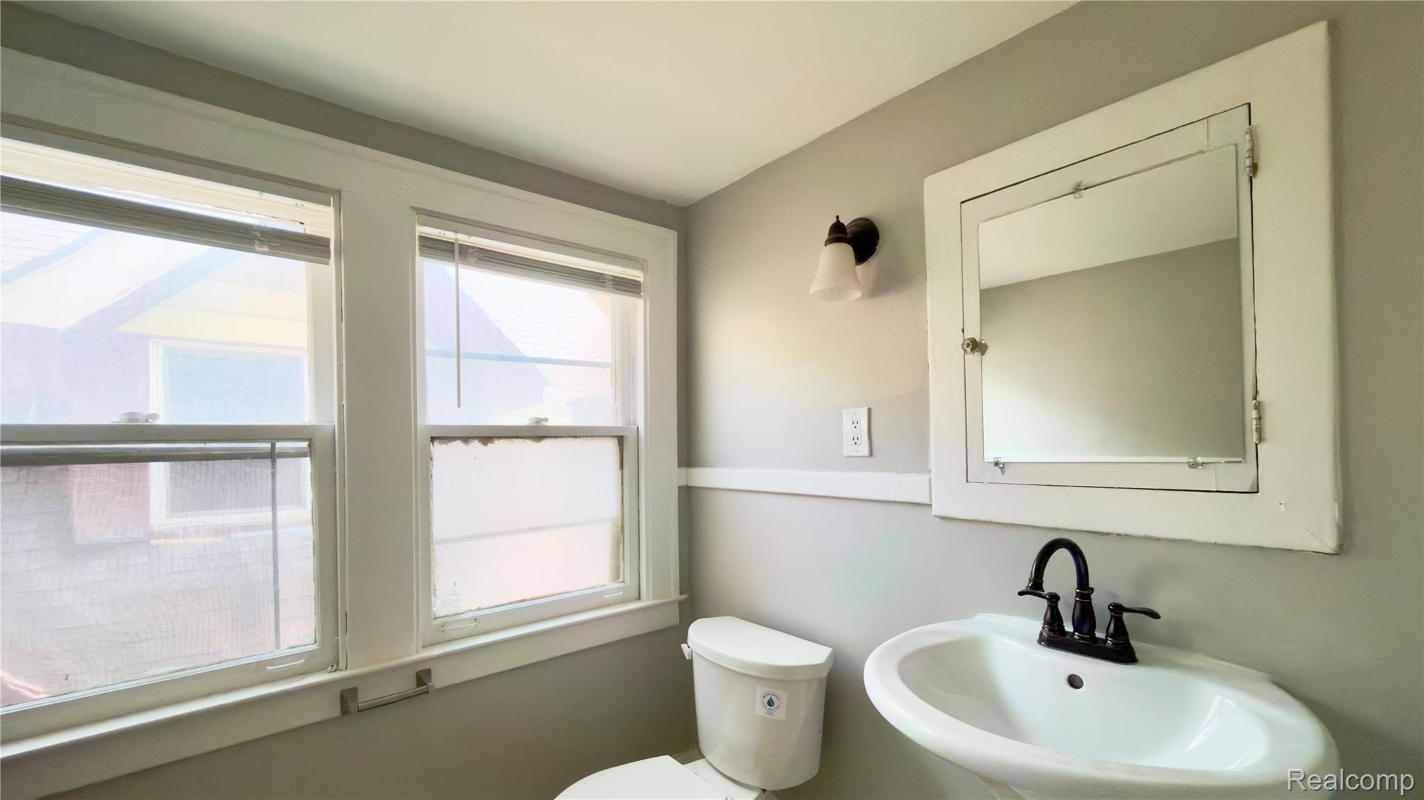 1651 Atkinson Street, Unit 3 Detroit, MI 48206 - Photo 11 of 11 Bathroom featuring a pedestal sink with a matte black faucet, wall-mounted mirror, and a sconce light fixture
