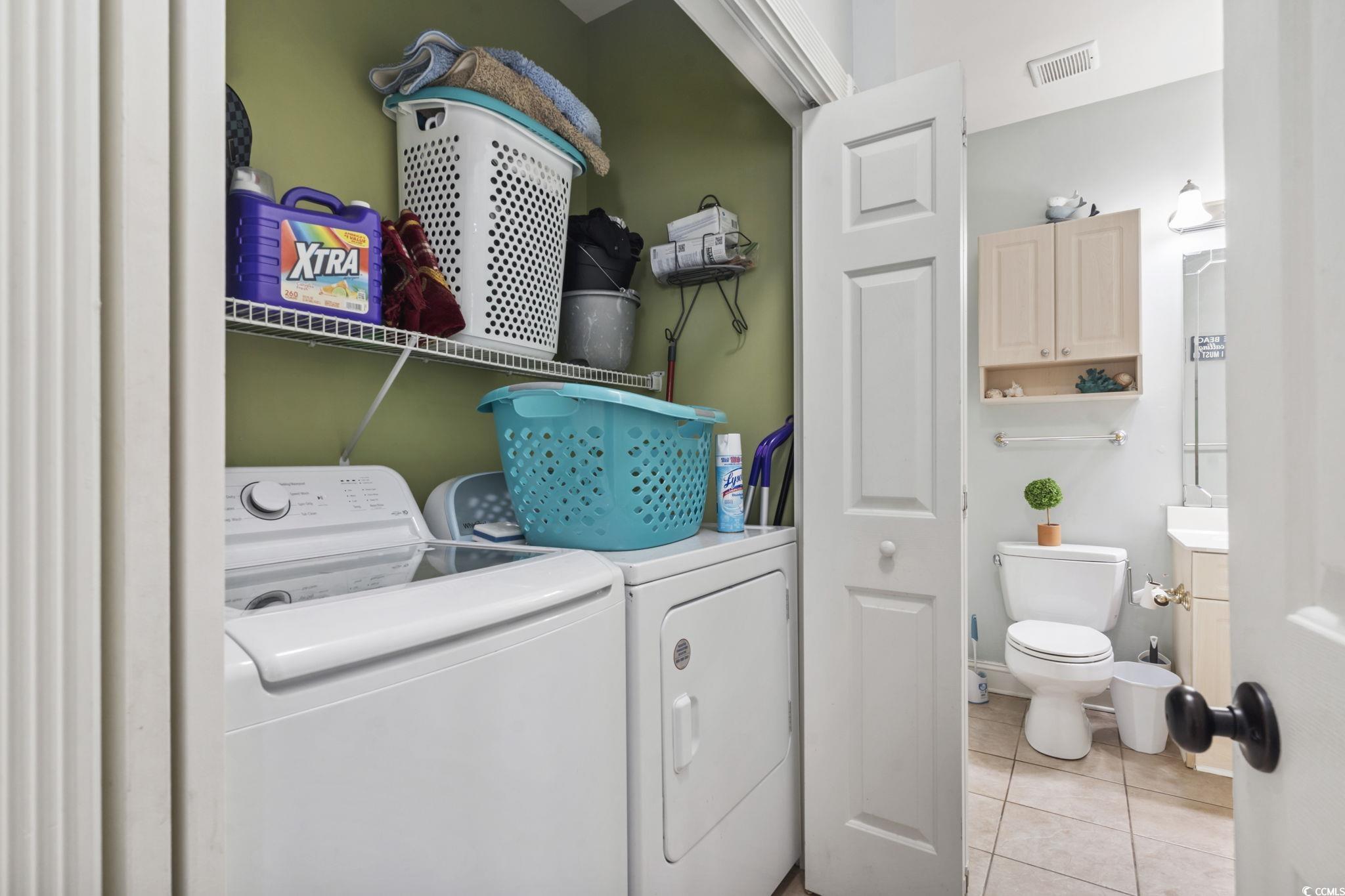 4847 Luster Leaf Circle, Unit 301 Myrtle Beach, SC 29577 - Photo 10 of 16 Laundry area with light tile patterned floors and washing machine and clothes dryer
