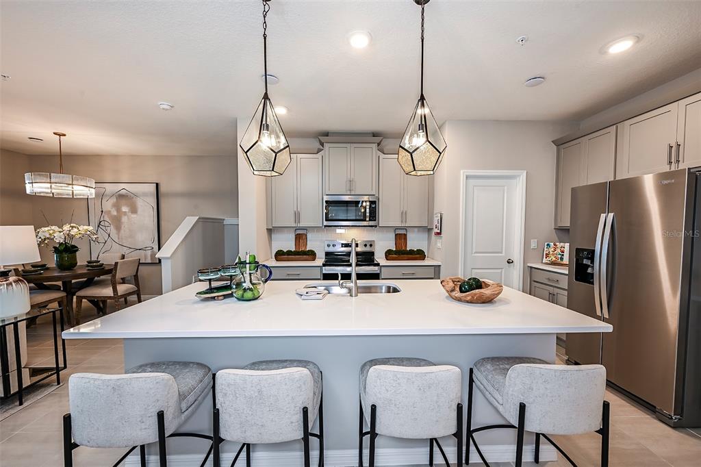 551 Southern Edge Way Sanford, FL 32771 - Photo 3 of 15 a kitchen with refrigerator a center island a dining table and chairs