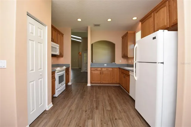 a kitchen with a refrigerator a sink and wooden floor