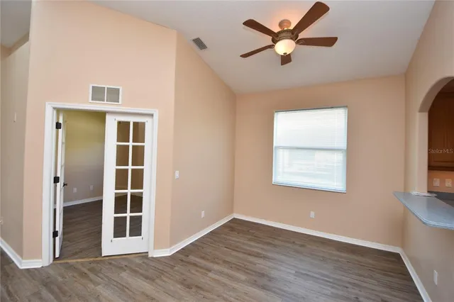 a view of an empty room with a window and wooden floor