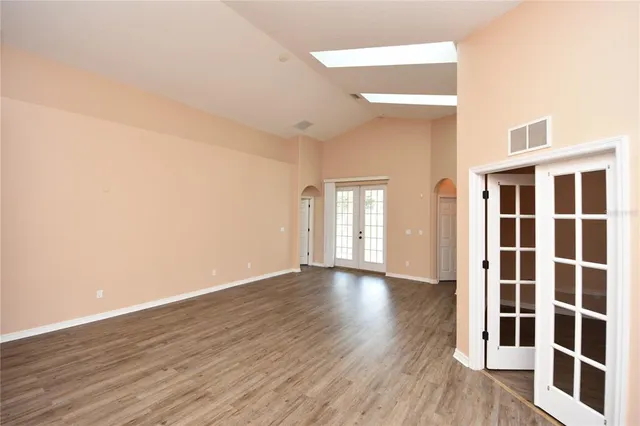 a view of an empty room with wooden floor and windows