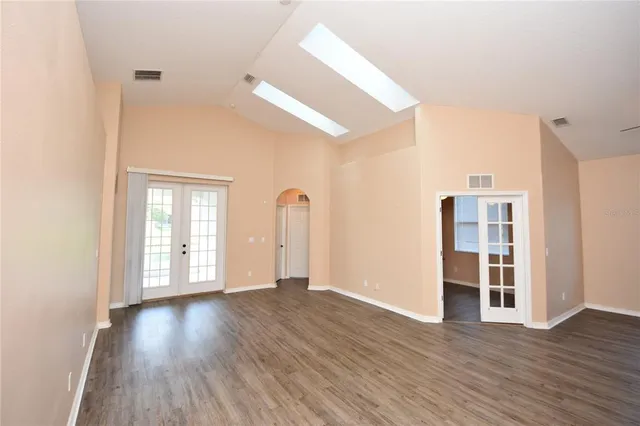 a view of an empty room with wooden floor and windows
