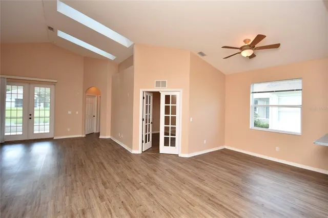 a view of empty room with wooden floor and fan