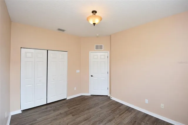an empty room with wooden floor and a ceiling fan