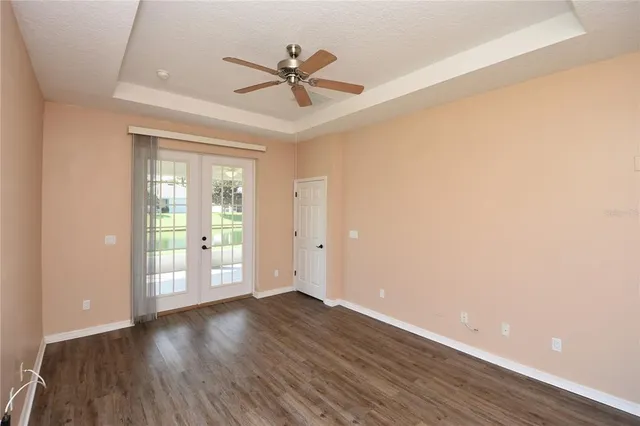 a view of an empty room with wooden floor and a ceiling fan