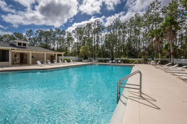 an aerial view of a house with swimming pool and large trees