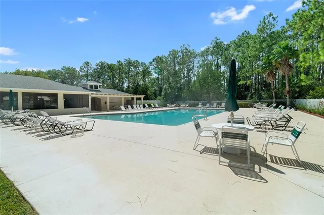 a view of a patio with a table and chairs under an umbrella with large trees