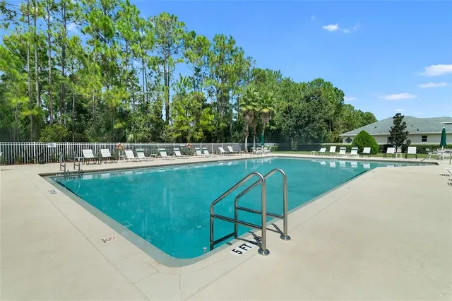 a view of a swimming pool with a bench and trees in the background