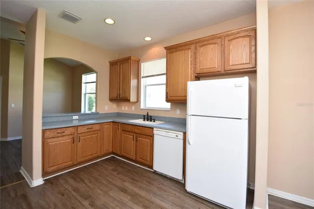 a kitchen with stainless steel appliances granite countertop a refrigerator a sink and white cabinets