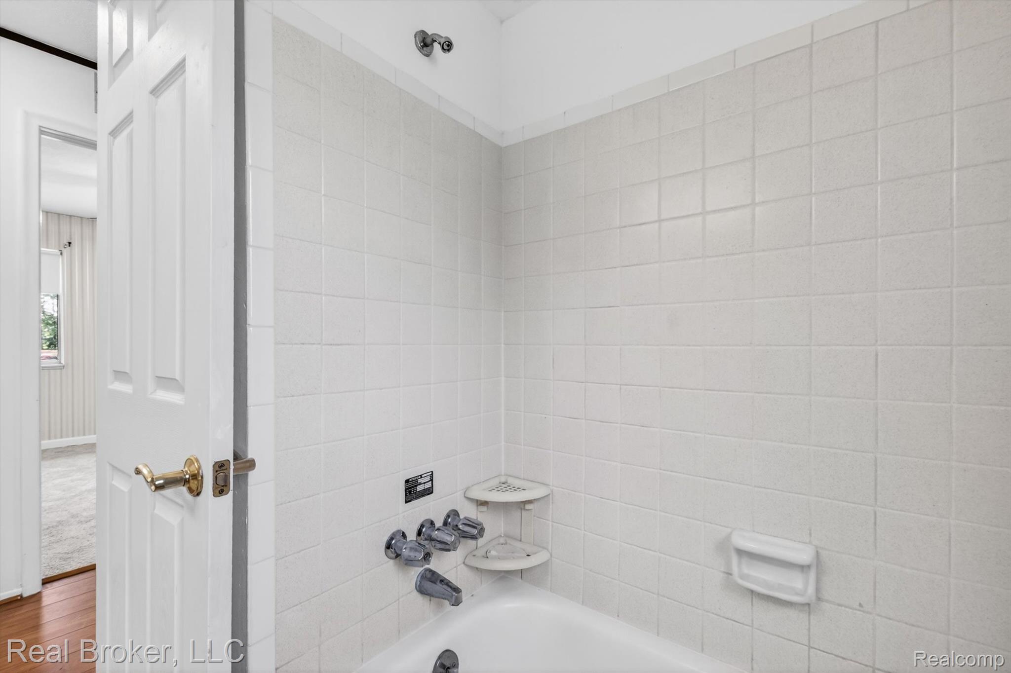 48050 Hull Road Belleville, MI 48111 - Photo 35 of 39 White ceramic tile shower surround with integrated soap dish and corner shelves, featuring a chrome showerhead and faucet set