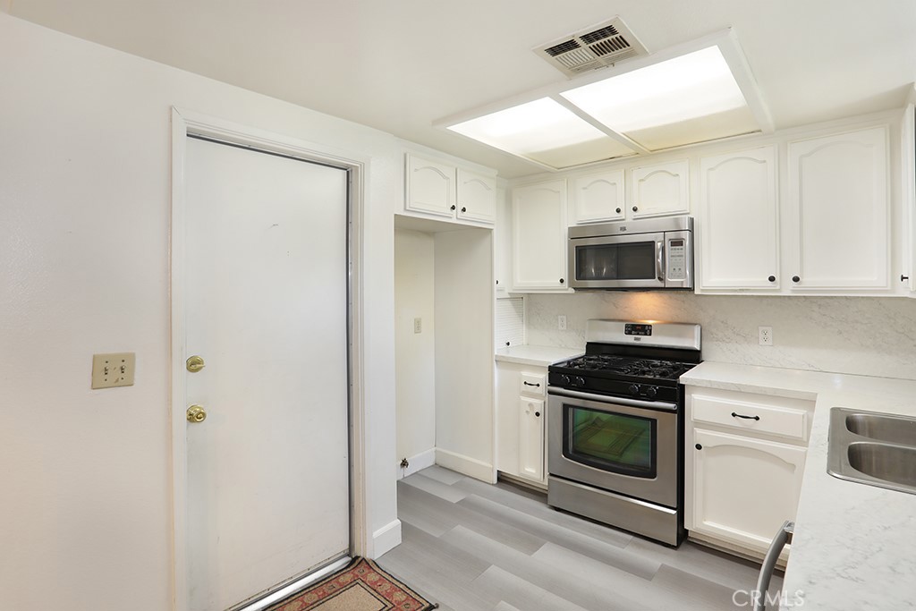 8032 Rose Street, Unit 13 Paramount, CA 90723 - Photo 11 of 25 a kitchen with a stove a microwave and white cabinets