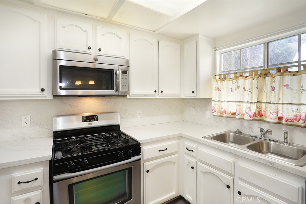 8032 Rose Street, Unit 13 Paramount, CA 90723 - Photo 12 of 25 a kitchen with cabinets stainless steel appliances and a sink