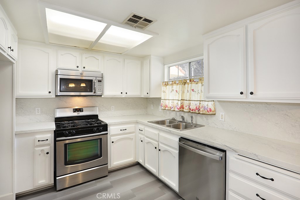 8032 Rose Street, Unit 13 Paramount, CA 90723 - Photo 10 of 25 a kitchen with cabinets stainless steel appliances and a sink