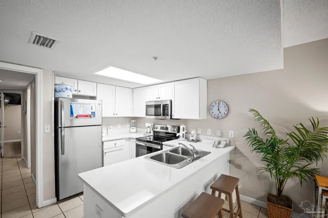 a kitchen with a refrigerator a sink a stove and white cabinets