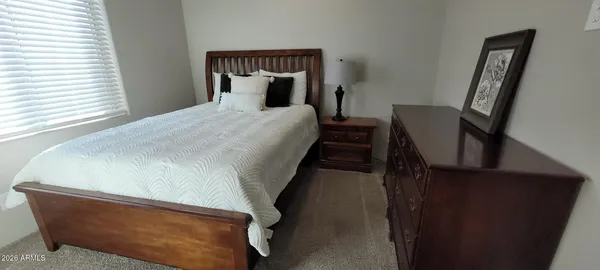 a bed sitting in a bedroom next to a window with chair and a potted plant