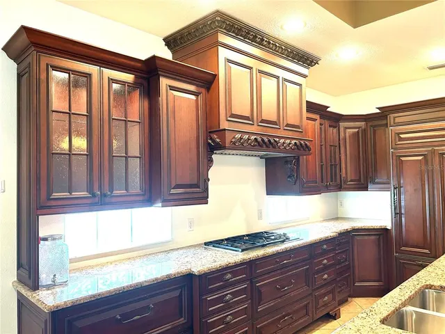 a kitchen with granite countertop wooden cabinets a sink and a window
