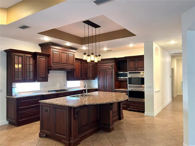 a large kitchen with stainless steel appliances kitchen island granite countertop a refrigerator and a stove top oven