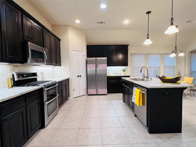 a large kitchen with stainless steel appliances wooden cabinets a stove a sink and a microwave