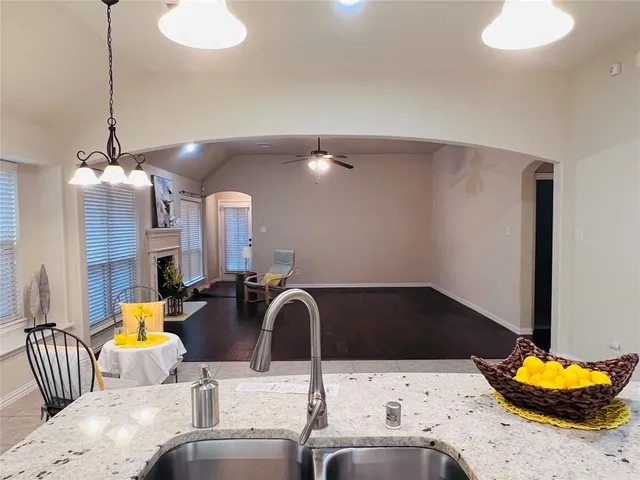 a kitchen with stainless steel appliances kitchen island granite countertop a sink and a chandelier