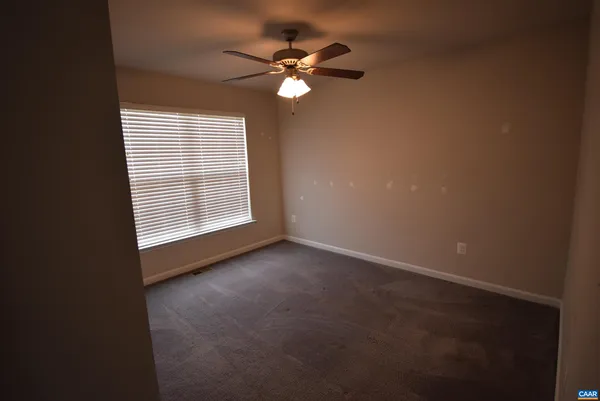 a view of an empty room with a ceiling fan and window