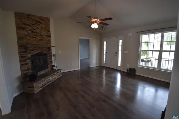an empty room with wooden floor fireplace and windows