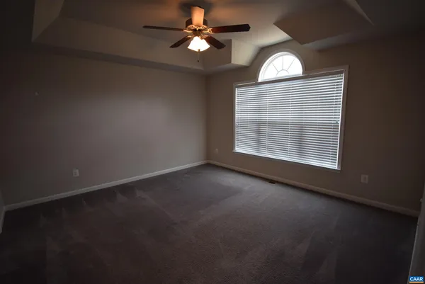 an empty room with a window and a fan