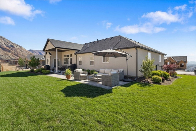 638 East Mountain Road North Ogden, UT 84414 - Photo 27 of 28 Enhanced staged back yard (Landscaping not included) Rear view of property featuring a lawn, stucco siding, a patio area, outdoor lounge area, and a mountain view