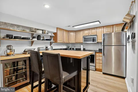 a kitchen with stainless steel appliances granite countertop a refrigerator a sink dishwasher a stove and a dining table with wooden floor