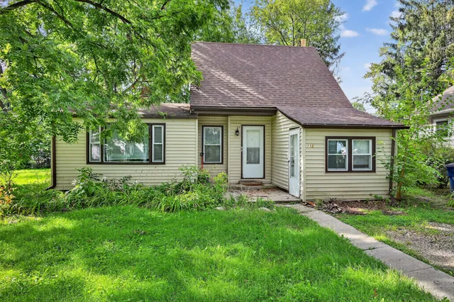 a view of a house with a yard plants and large tree