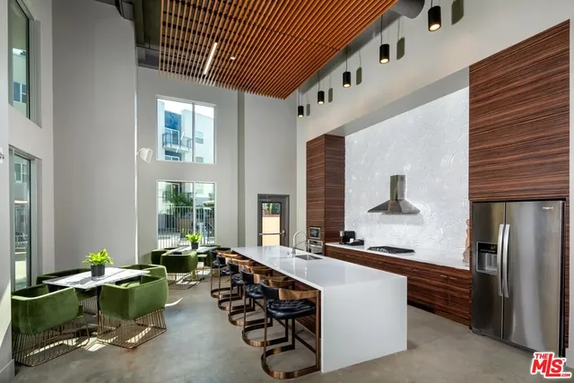 a large white kitchen with stainless steel appliances kitchen island granite countertop a refrigerator and a stove