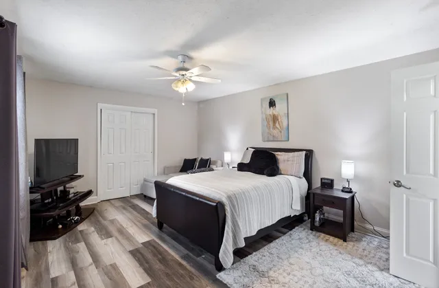 a bedroom with a bed a tv and wooden floor