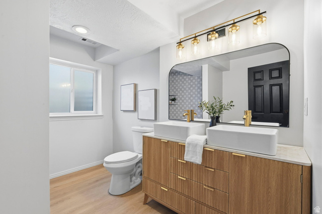 2460 Allison Way Syracuse, UT 84075 - Photo 17 of 24 Bathroom featuring a dual vanity with rectangular vessel sinks, gold-finish faucets, and a light wood-finish cabinet with textured fronts