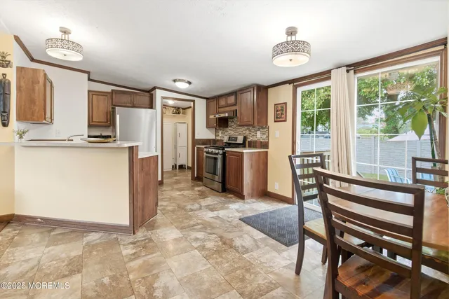 a kitchen with stainless steel appliances granite countertop a stove top oven a sink dishwasher a dining table and chairs with wooden floor