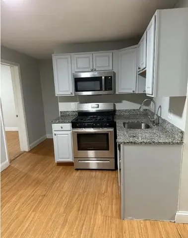 a kitchen with stainless steel appliances granite countertop a stove a sink and a microwave