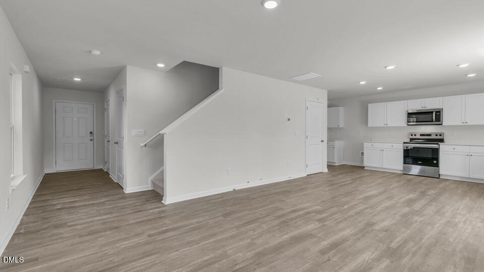 552 Stream Walk Crossing Wendell, NC 27591 - Photo 6 of 42 an empty room with wooden floor and kitchen view