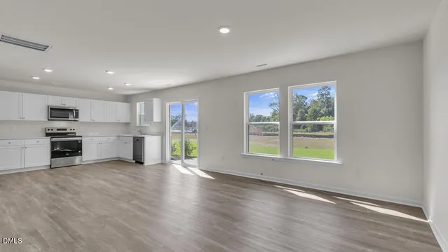 a view of an empty room with window and wooden floor
