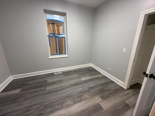 an empty room with wooden floor and window