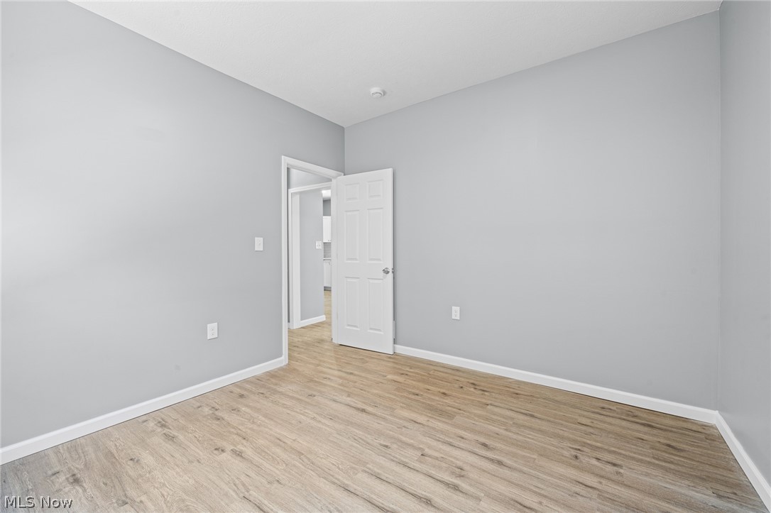 3925 Riverside Avenue Cleveland, OH 44109 - Photo 18 of 48 Room featuring light wood-finish flooring, light gray wall paint, white baseboards, and a white interior door