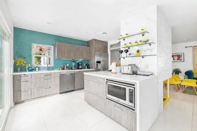 a kitchen with stainless steel appliances kitchen island granite countertop a refrigerator a stove and a sink with wooden cabinets