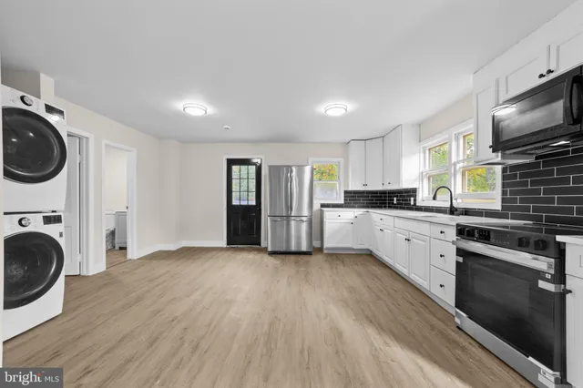 a view of a kitchen with a sink stainless steel appliances wooden floor and cabinets