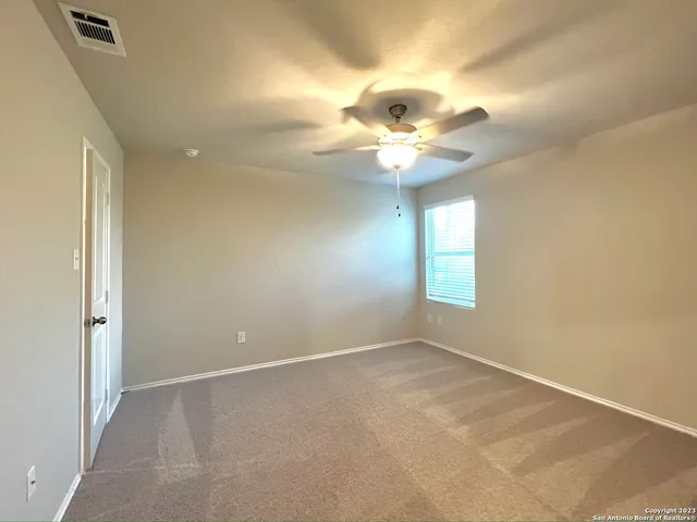 an empty room with a chandelier fan and windows