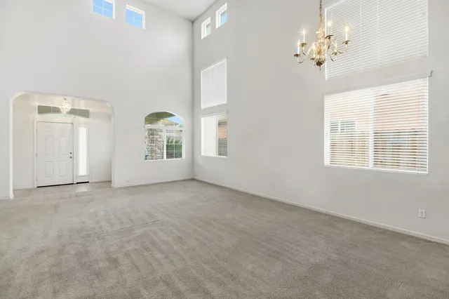 an empty room with windows a fireplace a ceiling fan and wooden floor